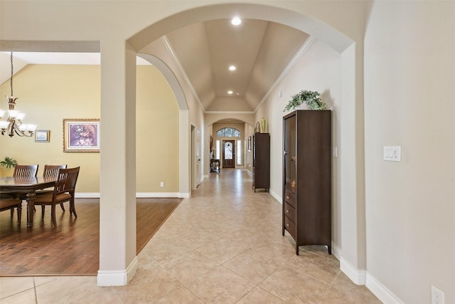 hallway with an inviting chandelier, light tile patterned floors, crown molding, and vaulted ceiling