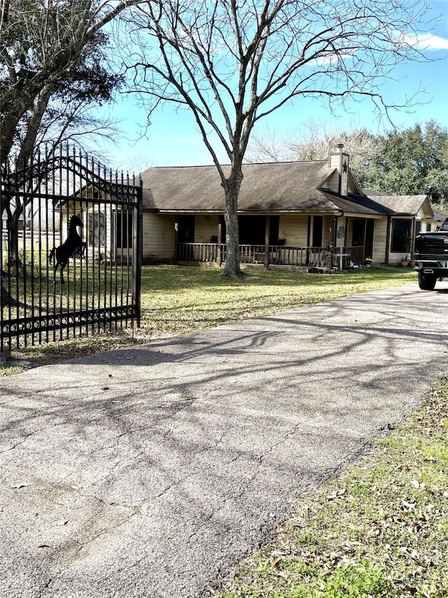 view of front facade featuring a gate, driveway, and a chimney