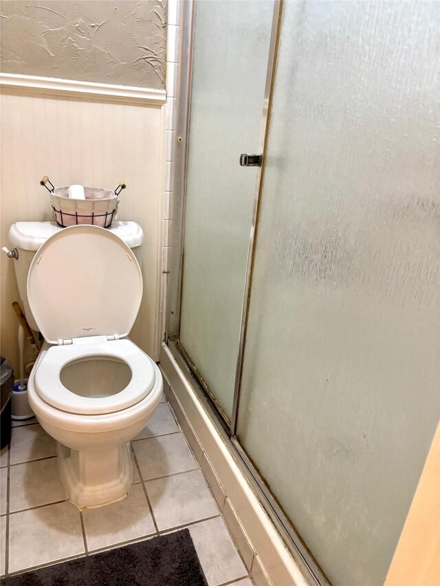 bathroom with tile patterned floors, toilet, and walk in shower