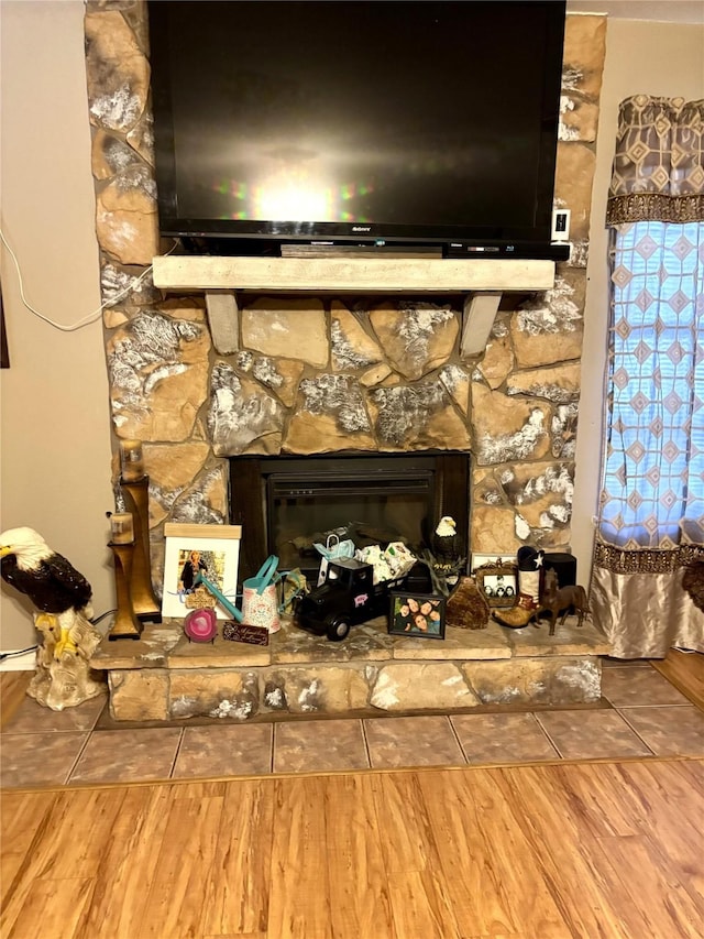 interior details featuring a stone fireplace and wood-type flooring