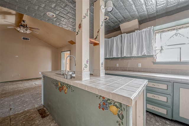 kitchen with ceiling fan, tile counters, and vaulted ceiling