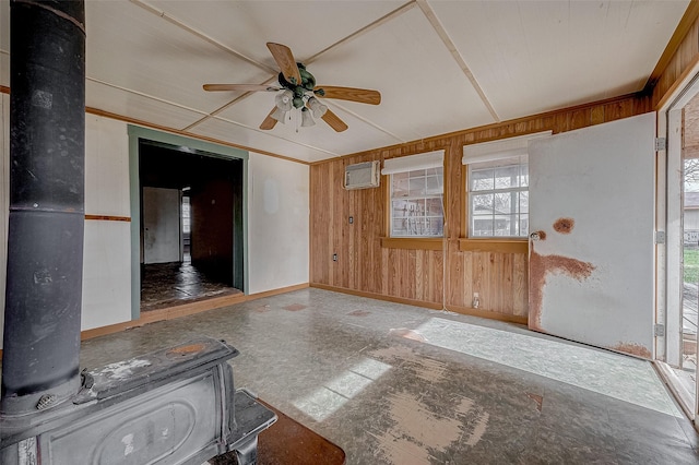 unfurnished living room featuring wooden walls, a wall unit AC, ceiling fan, and a wood stove