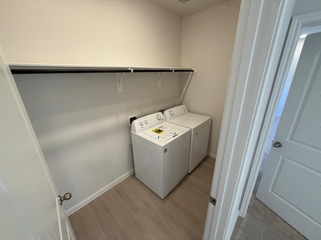 washroom with washing machine and clothes dryer and light hardwood / wood-style flooring