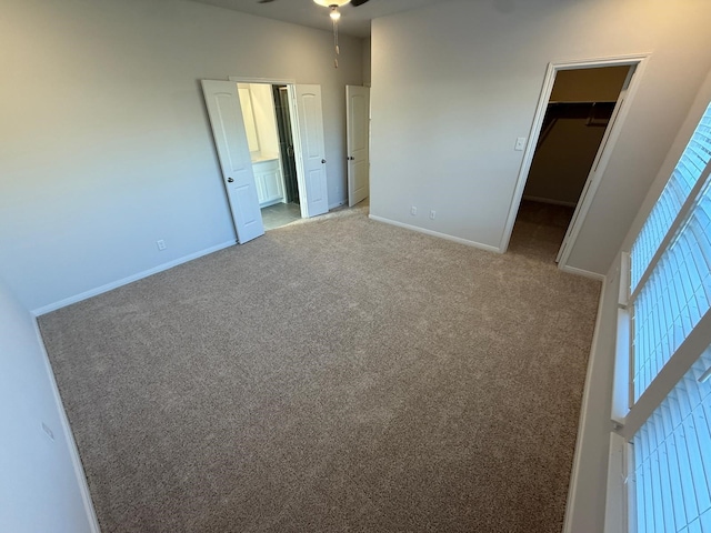 unfurnished bedroom featuring a spacious closet, light carpet, and a closet