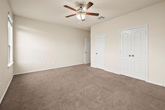 unfurnished bedroom with ceiling fan and dark carpet