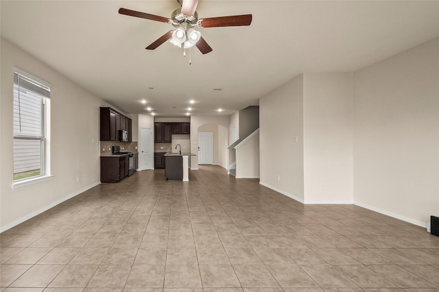 unfurnished living room featuring sink, light tile patterned floors, and ceiling fan