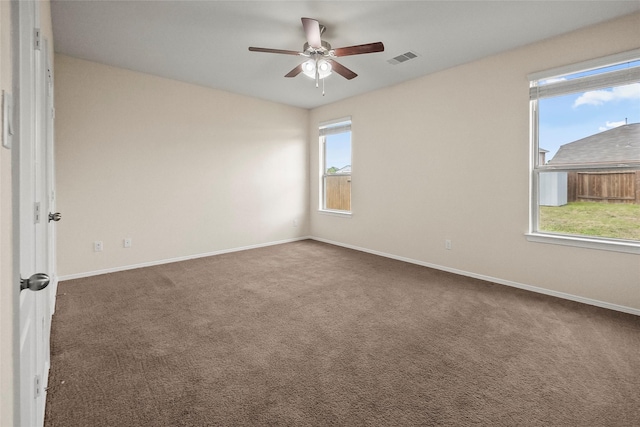 unfurnished room with dark colored carpet and ceiling fan