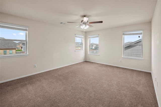 empty room with carpet, a wealth of natural light, and ceiling fan