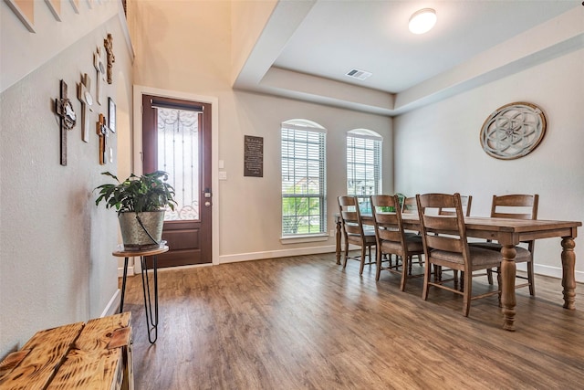 dining space featuring hardwood / wood-style floors and a raised ceiling