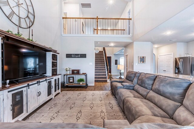 living room featuring a towering ceiling and light wood-type flooring