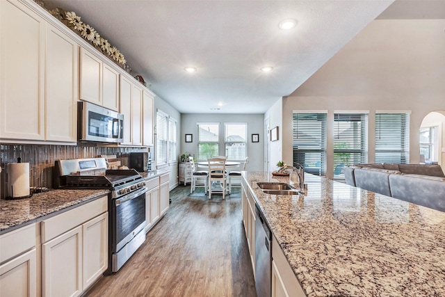 kitchen with light stone counters, white cabinetry, appliances with stainless steel finishes, and sink