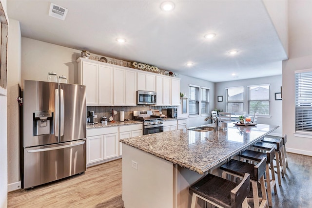 kitchen featuring sink, stainless steel appliances, an island with sink, and white cabinets