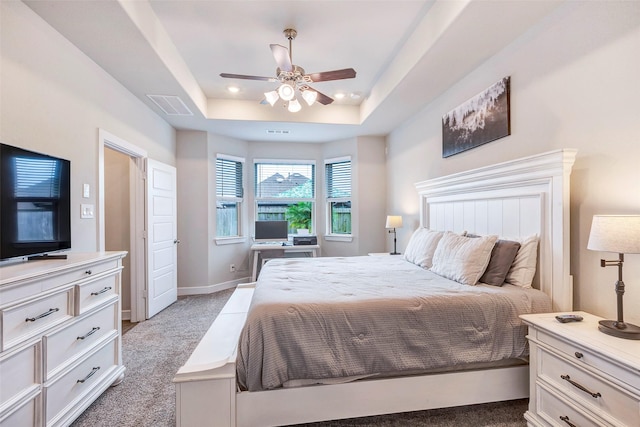 bedroom featuring light colored carpet, ceiling fan, and a tray ceiling