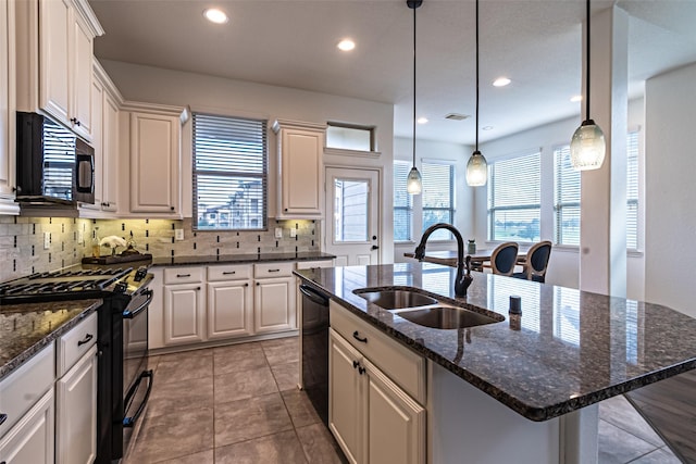 kitchen featuring an island with sink, sink, white cabinets, hanging light fixtures, and black appliances