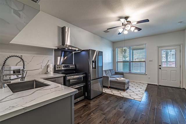 kitchen with appliances with stainless steel finishes, dark hardwood / wood-style floors, sink, light stone counters, and wall chimney range hood