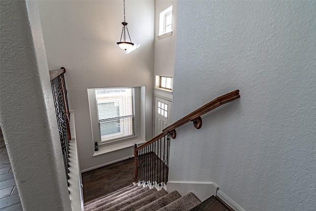 stairway with hardwood / wood-style flooring and a high ceiling