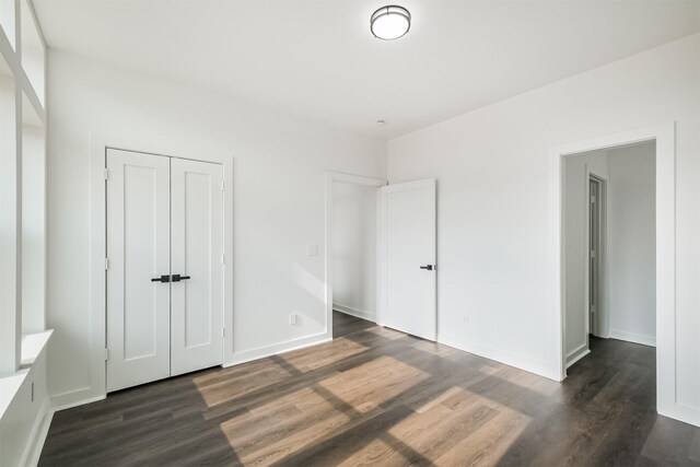 unfurnished bedroom with dark wood-type flooring and a closet