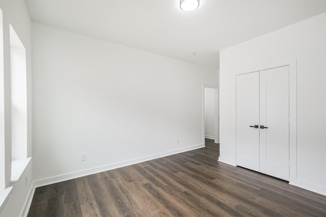 unfurnished bedroom with dark hardwood / wood-style flooring and a closet