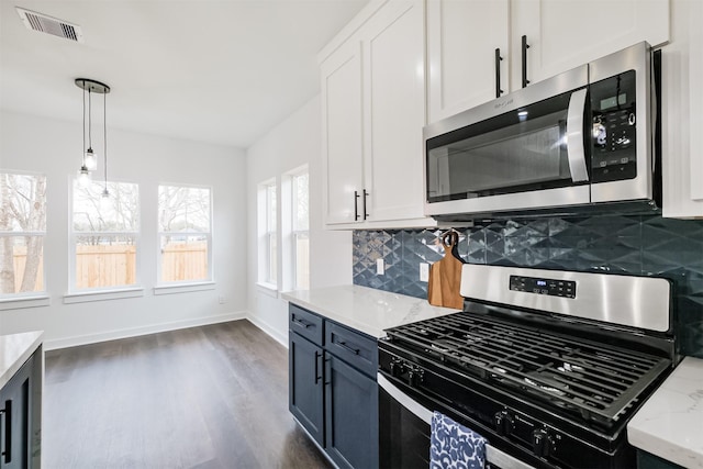 kitchen with appliances with stainless steel finishes, decorative light fixtures, white cabinets, decorative backsplash, and light stone counters