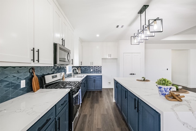 kitchen with appliances with stainless steel finishes, decorative light fixtures, white cabinets, dark hardwood / wood-style flooring, and blue cabinetry