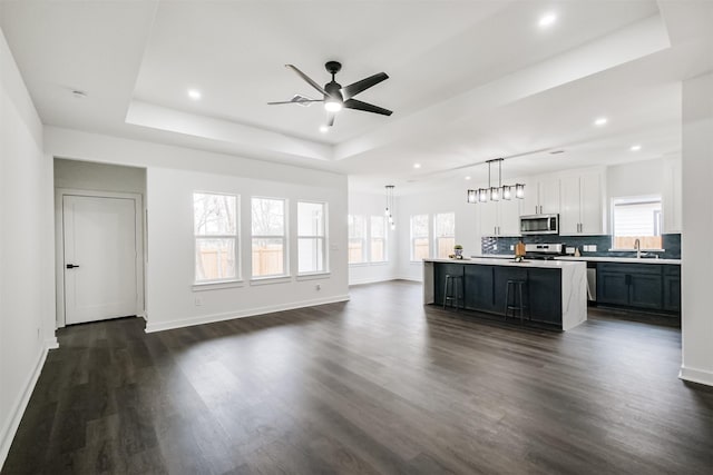 kitchen with pendant lighting, white cabinetry, stainless steel appliances, a center island, and a tray ceiling