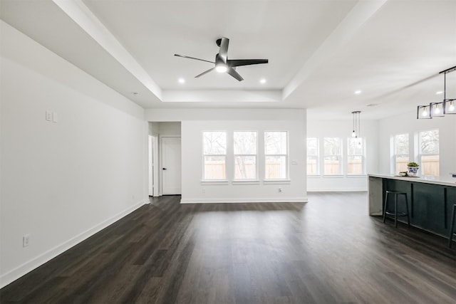 unfurnished living room with ceiling fan, dark hardwood / wood-style flooring, and a raised ceiling