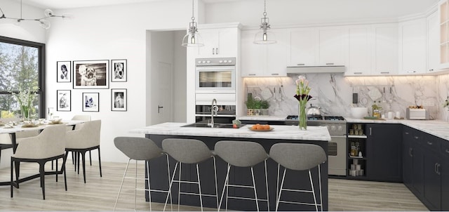 kitchen with white cabinetry, light stone countertops, stainless steel appliances, and a center island with sink