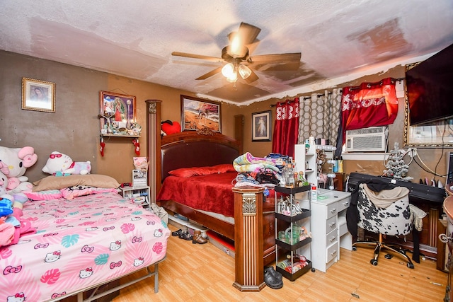 bedroom with hardwood / wood-style flooring, ceiling fan, cooling unit, and a textured ceiling