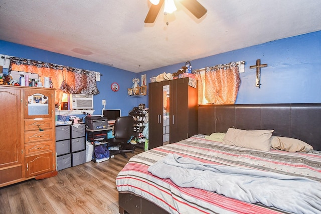 bedroom featuring hardwood / wood-style flooring, ceiling fan, cooling unit, and a textured ceiling