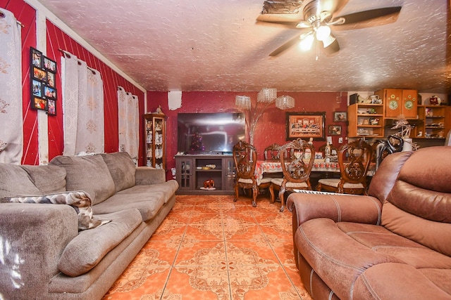 living room featuring ceiling fan, ornamental molding, tile patterned flooring, and a textured ceiling