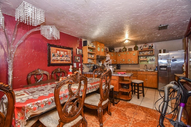 dining space featuring light tile patterned flooring, sink, and a textured ceiling