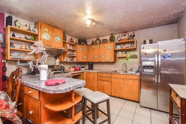 kitchen featuring sink, a breakfast bar, stainless steel appliances, light tile patterned flooring, and kitchen peninsula