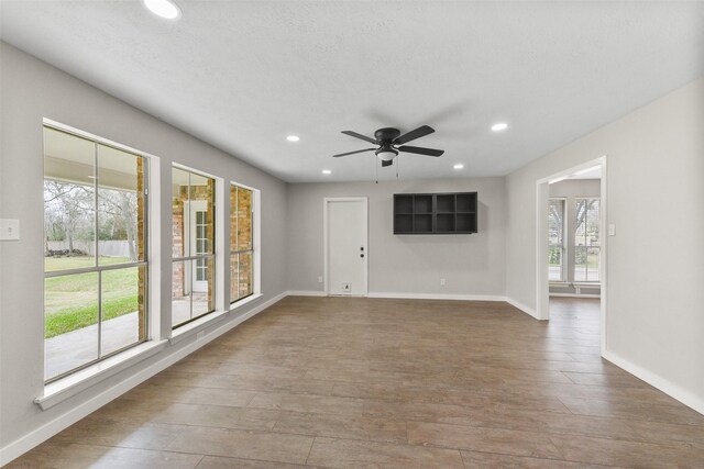 unfurnished living room featuring ceiling fan, hardwood / wood-style floors, and a textured ceiling