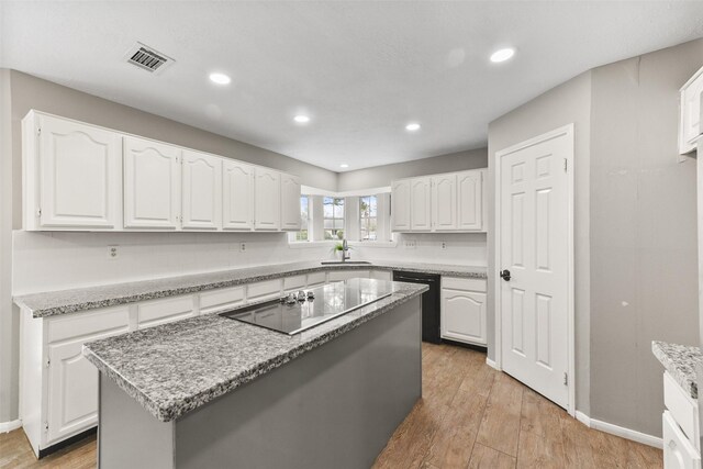 kitchen with sink, black appliances, a center island, and white cabinets