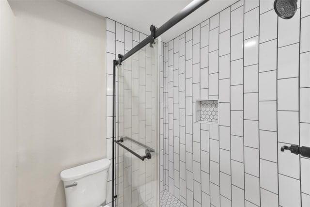 bathroom with tiled shower and toilet