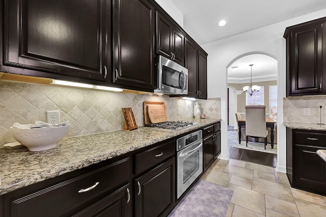 kitchen featuring a chandelier, light tile patterned floors, stainless steel appliances, light stone countertops, and decorative backsplash