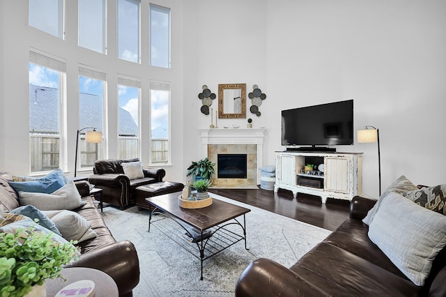 living room with a tiled fireplace, hardwood / wood-style flooring, and a high ceiling