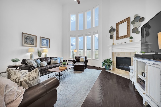 living room with dark wood-type flooring, a towering ceiling, and a fireplace