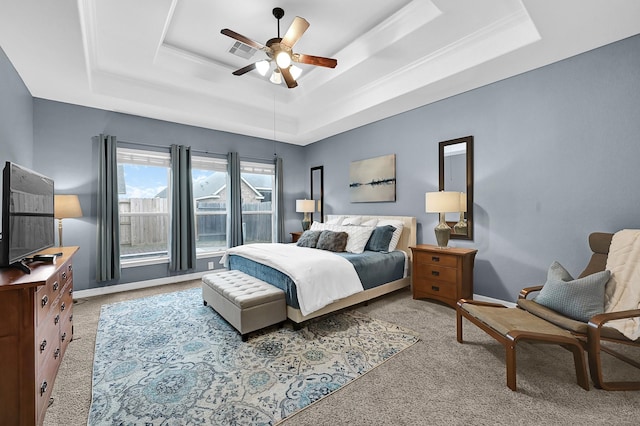 bedroom with light colored carpet, ceiling fan, and a tray ceiling