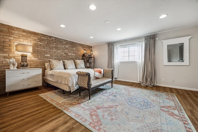 bedroom featuring brick wall and dark wood-type flooring