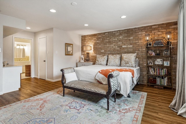 bedroom with hardwood / wood-style floors, ensuite bath, and brick wall