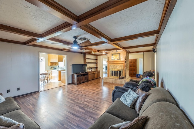 living room with beam ceiling, hardwood / wood-style flooring, a fireplace, and coffered ceiling