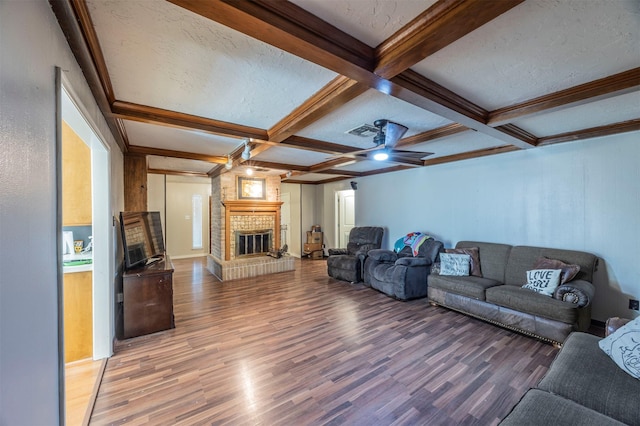 living room featuring coffered ceiling, beamed ceiling, ceiling fan, a fireplace, and hardwood / wood-style floors