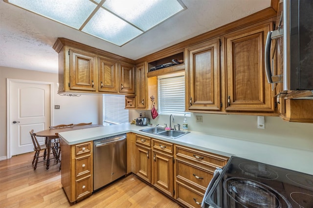 kitchen with stainless steel appliances, sink, light wood-type flooring, and kitchen peninsula