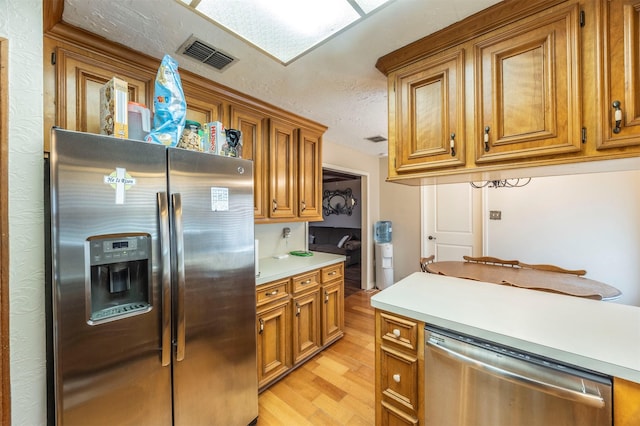 kitchen featuring stainless steel appliances, light hardwood / wood-style floors, and a textured ceiling