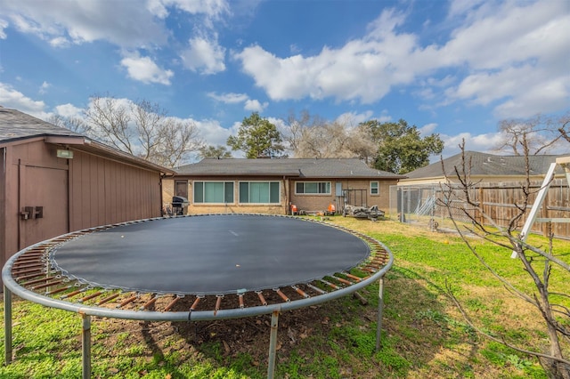 back of property featuring a yard and a trampoline