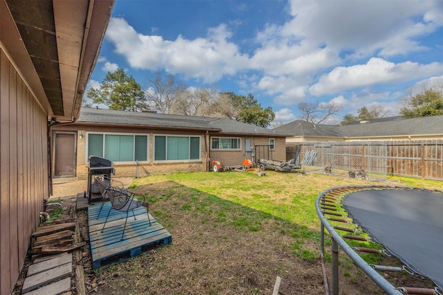 rear view of house with a yard and a trampoline