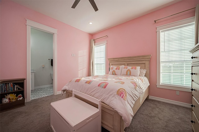 bedroom with ceiling fan, ensuite bathroom, and dark colored carpet