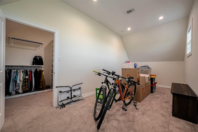 workout area featuring vaulted ceiling and light colored carpet