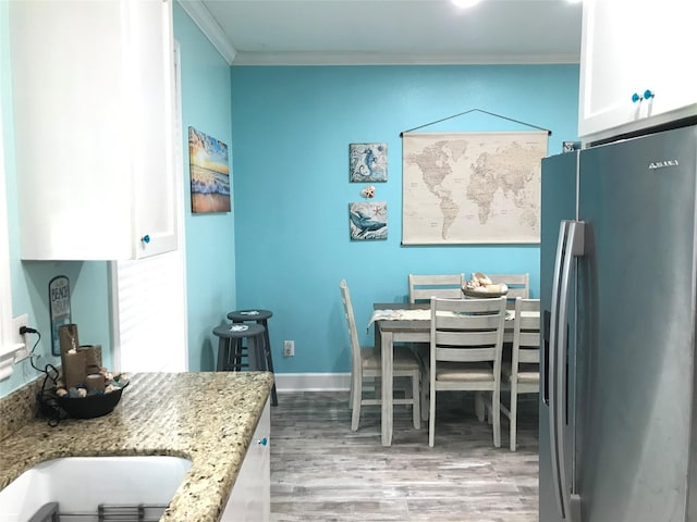 dining room with crown molding and light hardwood / wood-style flooring